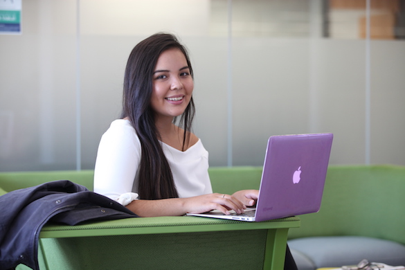 A student smiling while using a laptop